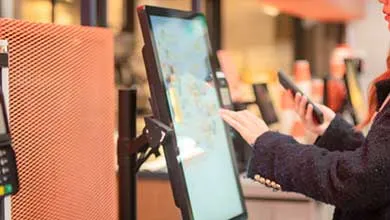 Person using a smartphone to interact with a self-service restaurant kiosk.