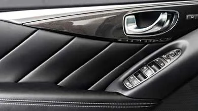 Close-up of a car's black leather interior door panel with a chrome handle and window/lock controls on the armrest.