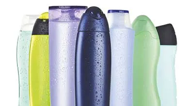Colorful shampoo and body wash bottles, wet with water droplets.