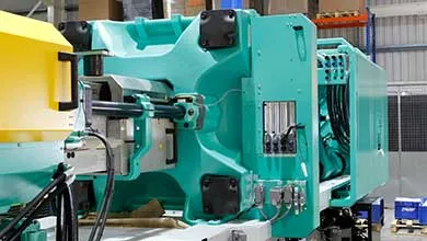 Close-up of a large teal industrial machine inside a factory.