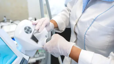 Technician wearing protective gloves operating laboratory testing equipment.