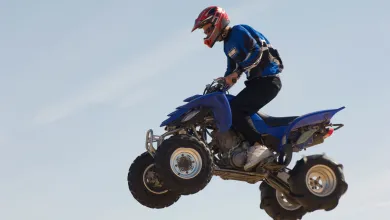 person riding an all‑terrain vehicle jumping through the air against a clear sky.