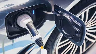 Electric vehicle plugged into a charging station, showing the charging connector attached to the vehicle port.