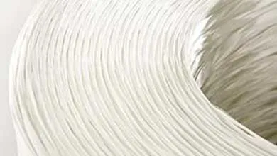 Close-up of a large spool with tightly wound white fibers, showing a curved, textured surface.